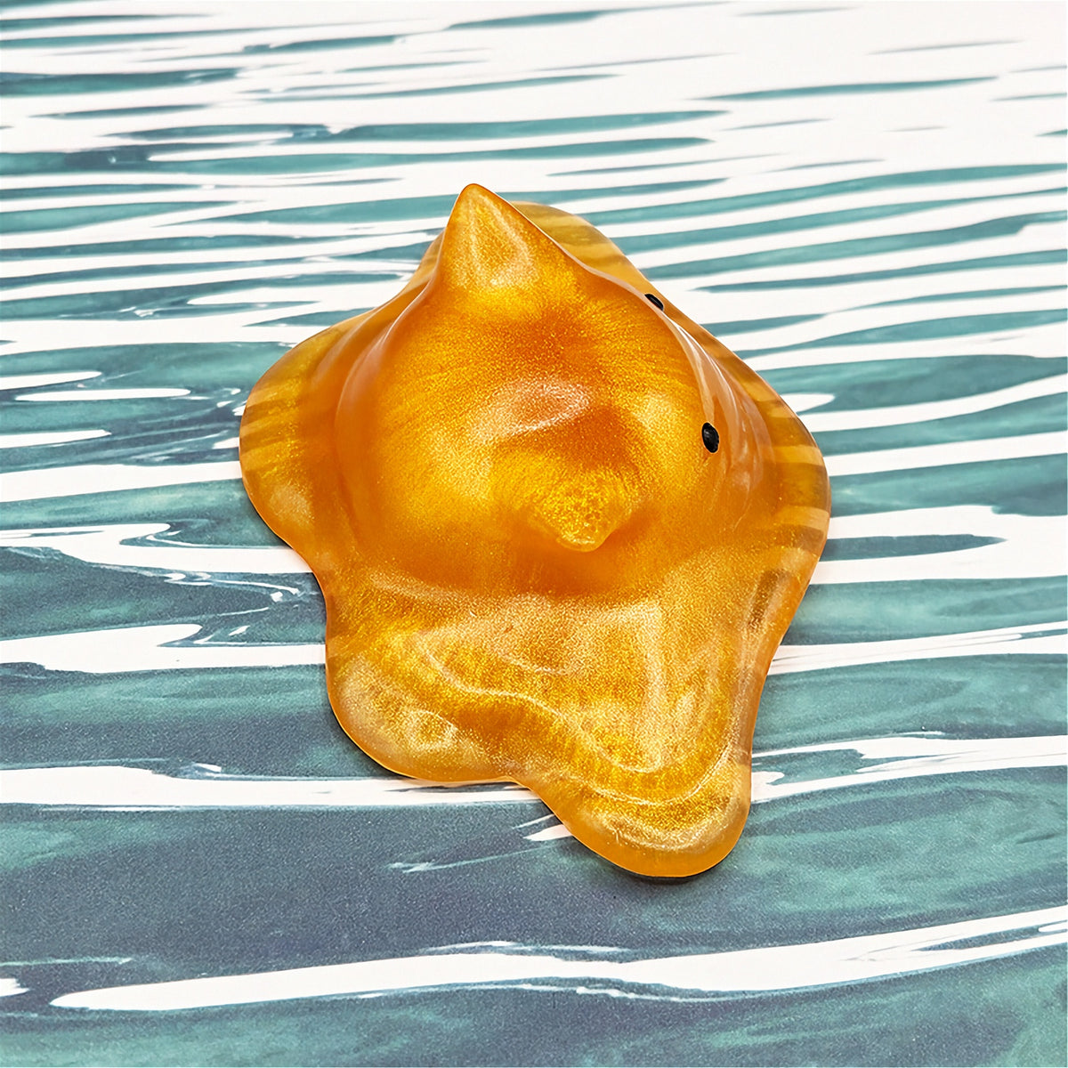 Cat-shaped resin blob on a striped background