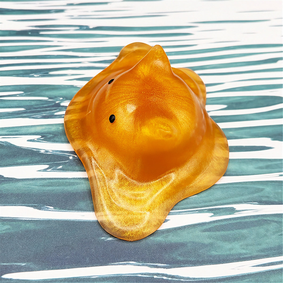Cat-shaped resin blob on a striped background