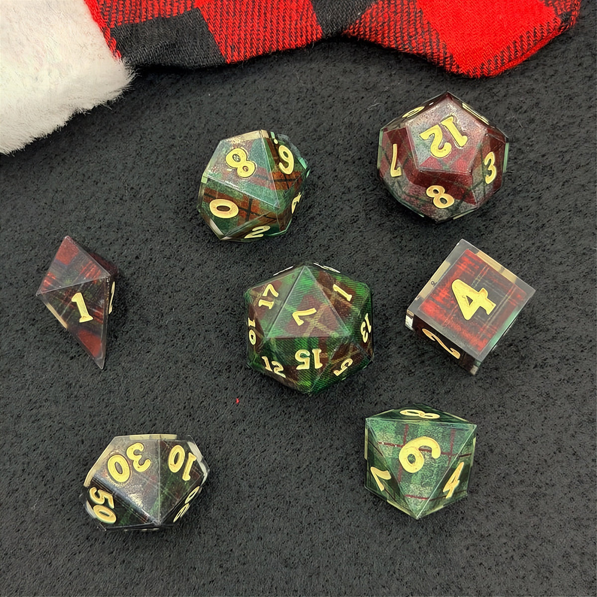 Set of polyhedral dice with red and black plaid fabric and white fur stocking background