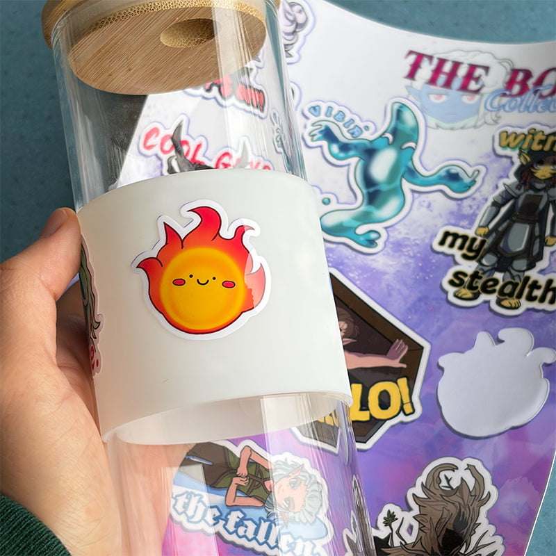 Clear glass tumbler with a white lid featuring a flame design, held in front of a colorful poster.