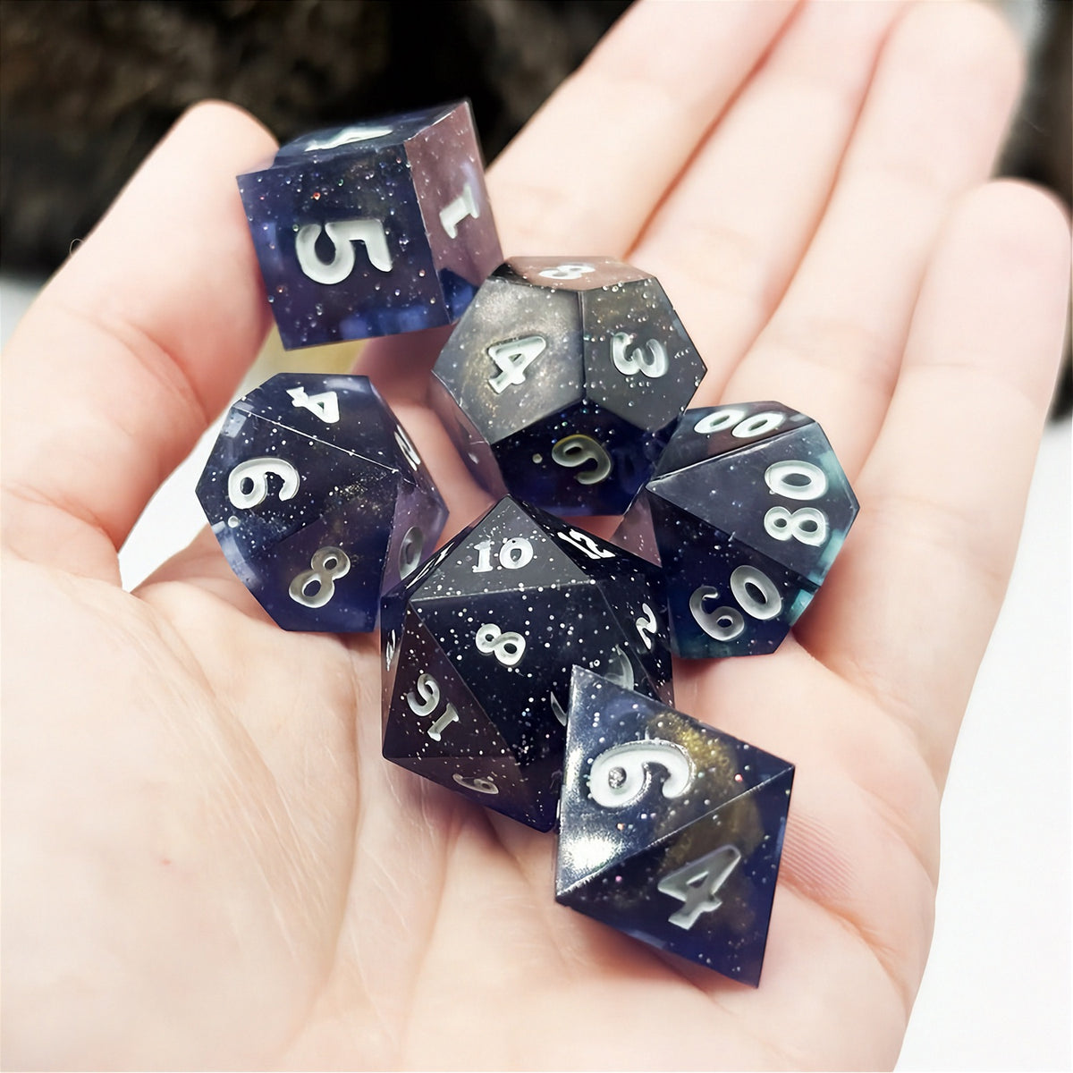 Set of polyhedral dice in a tin with star and moon pattern