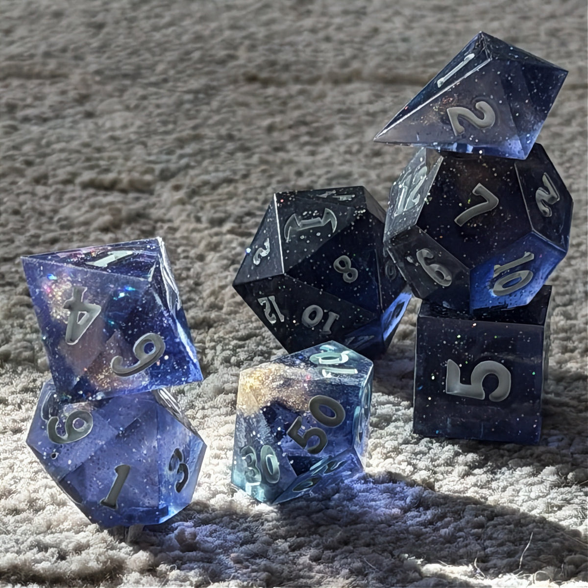 Set of polyhedral dice in a tin with star and moon pattern