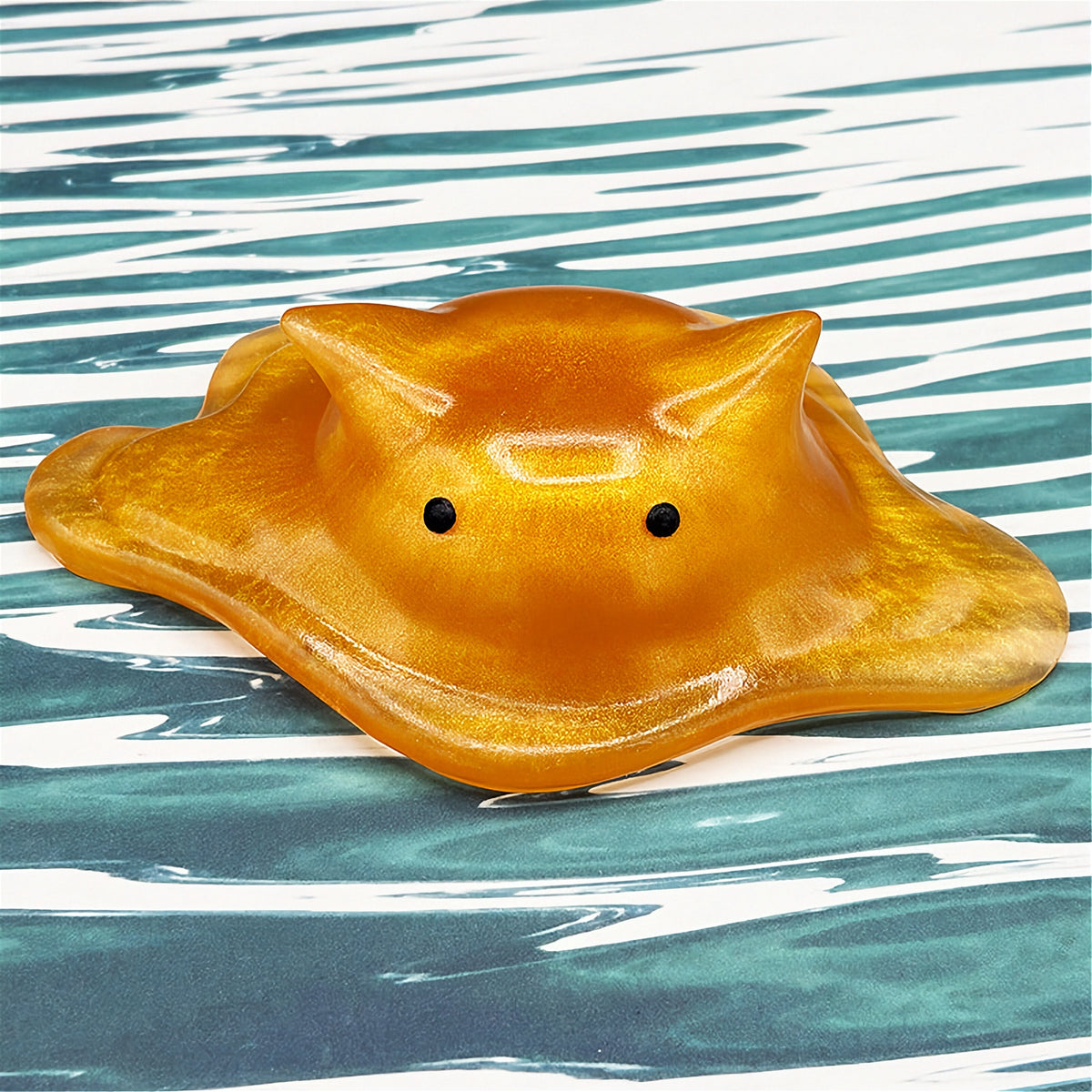 Cat-shaped resin blob on a striped background