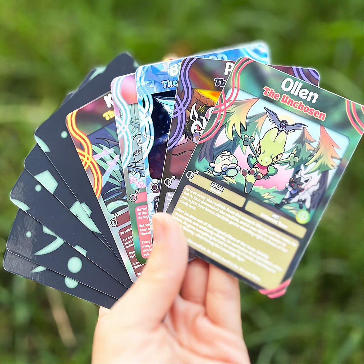 A hand holds a cartoon sticker next to a printed card pack titled "CopyCards Faithful Flock" on grass outdoors.