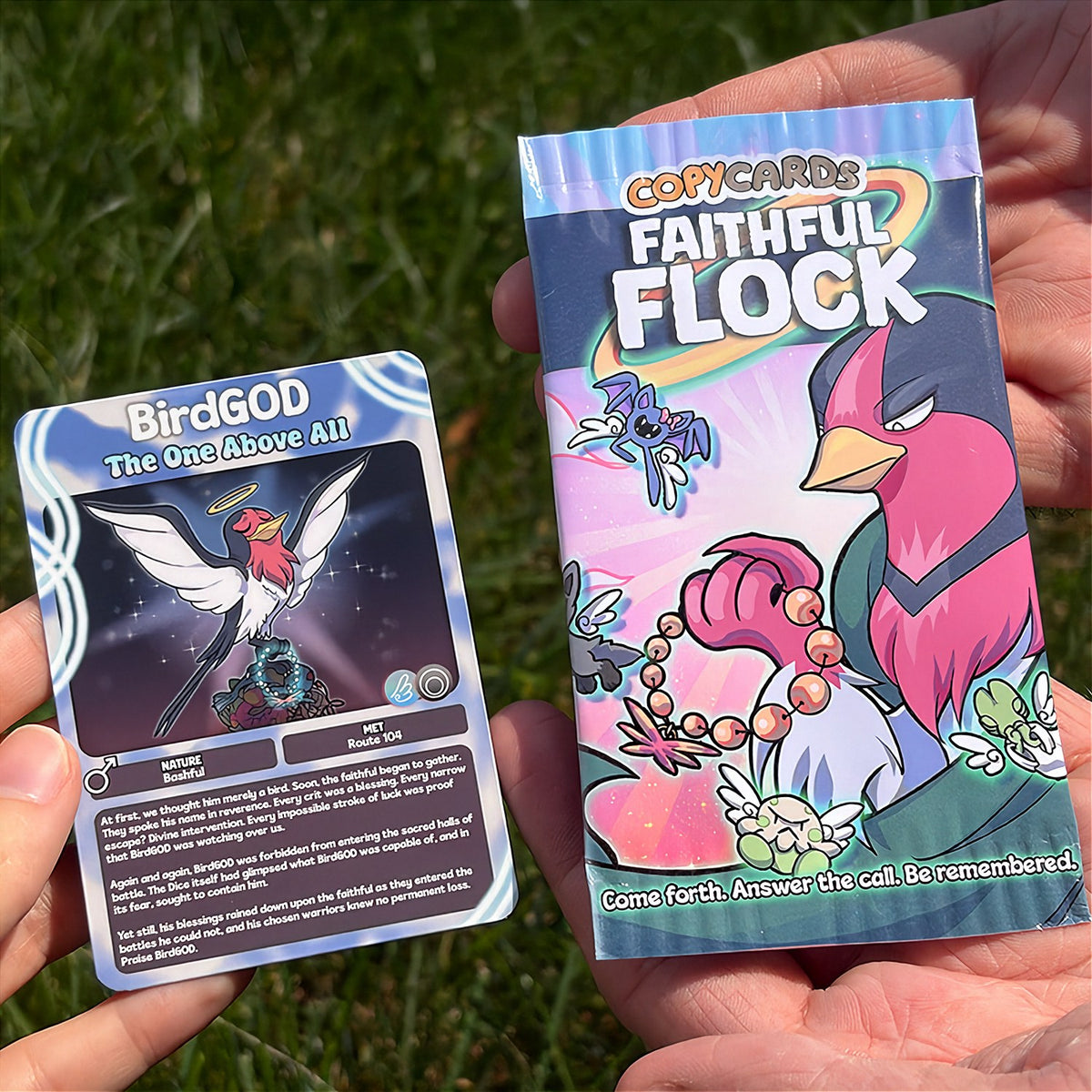 A hand holds a cartoon sticker next to a printed card pack titled "CopyCards Faithful Flock" on grass outdoors.