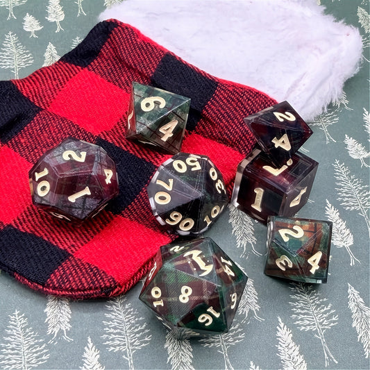Set of polyhedral dice with red and black plaid fabric and white fur stocking background