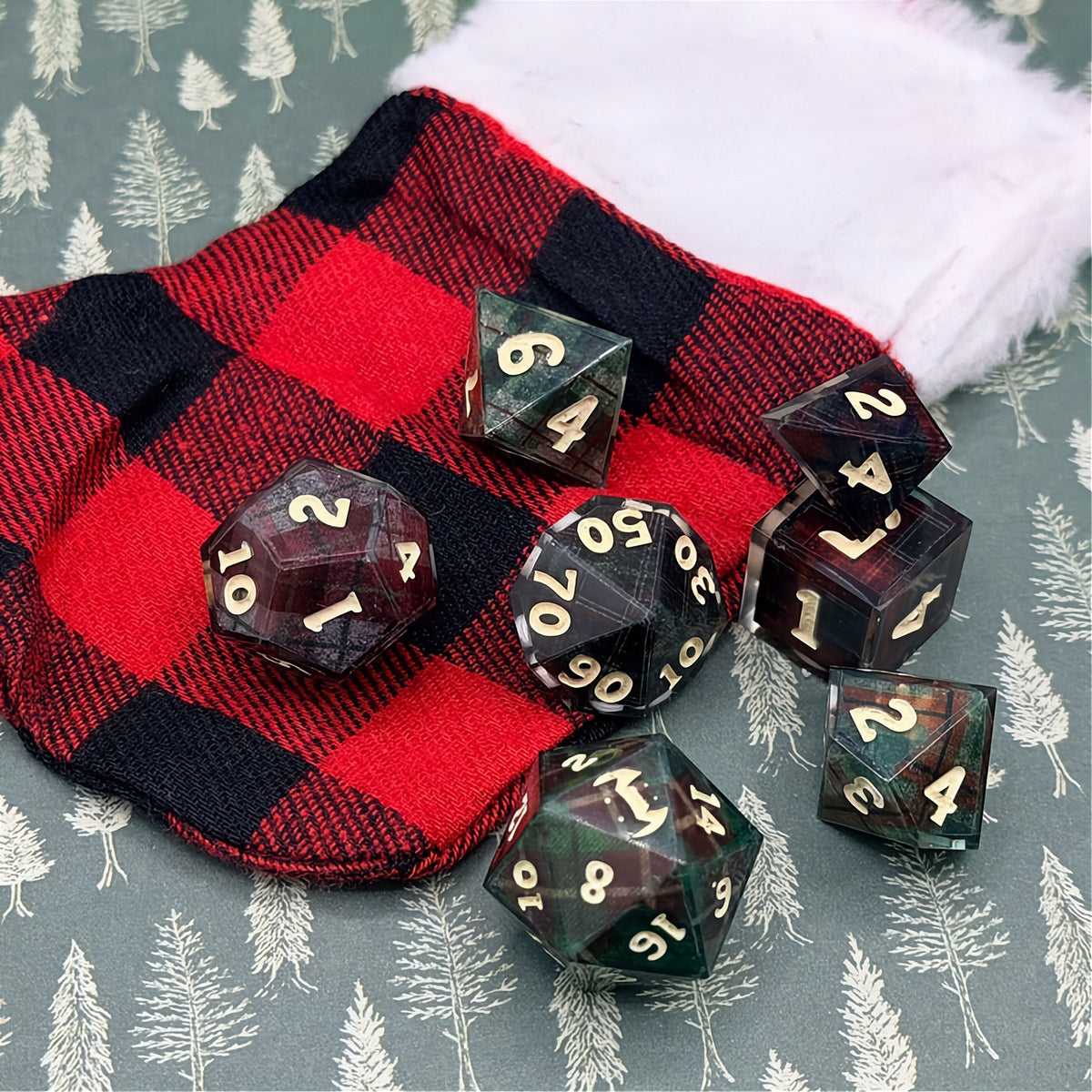 Set of polyhedral dice with red and black plaid fabric and white fur stocking background