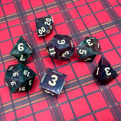 Set of polyhedral dice with red and black plaid fabric and white fur stocking background