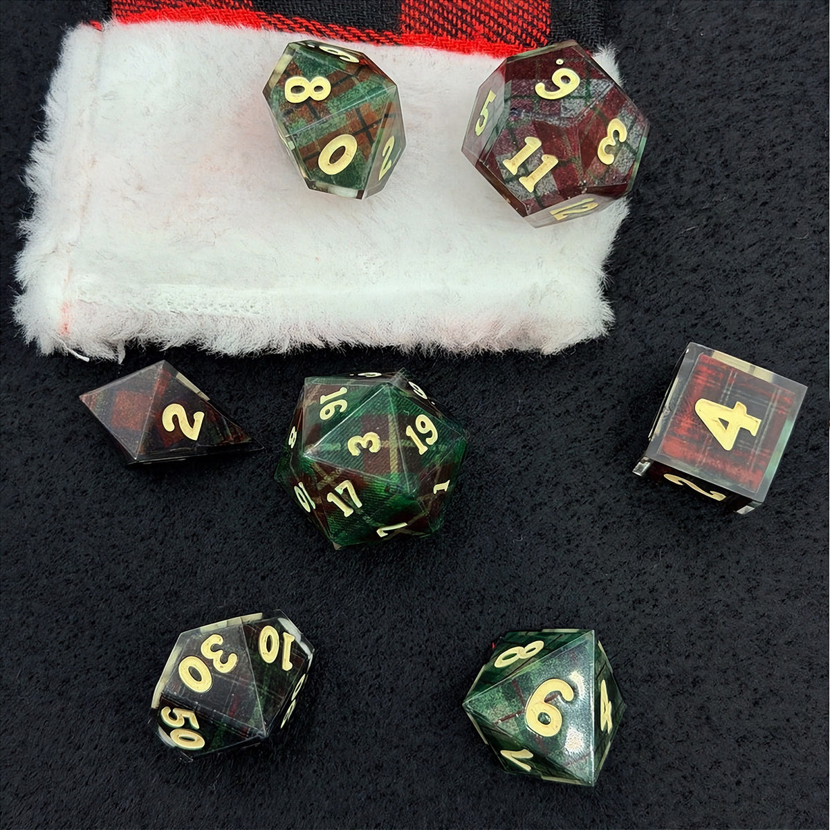 Set of polyhedral dice with red and black plaid fabric and white fur stocking background