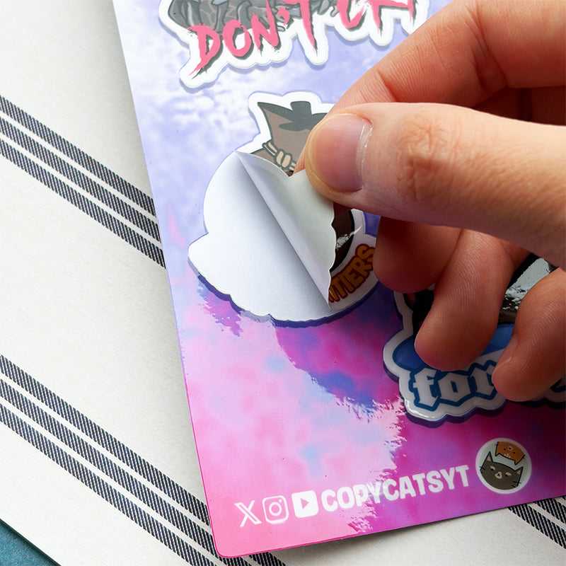 Hand holding a cat-themed sticker over a colorful card with 'COPYCATSYT' branding.