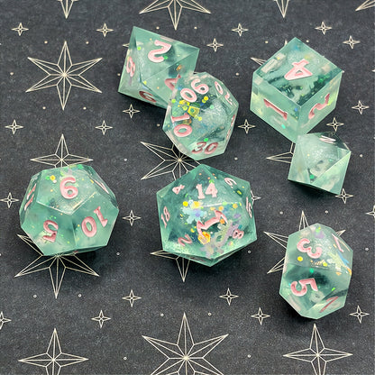 Set of green polyhedral dice with pink numbers on a dark background with star patterns