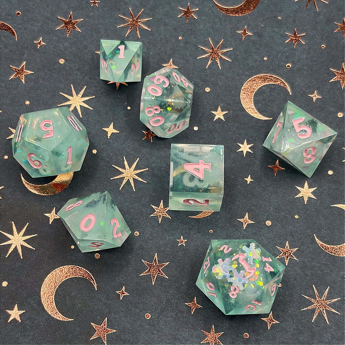 Set of green polyhedral dice with pink numbers on a dark background with star patterns