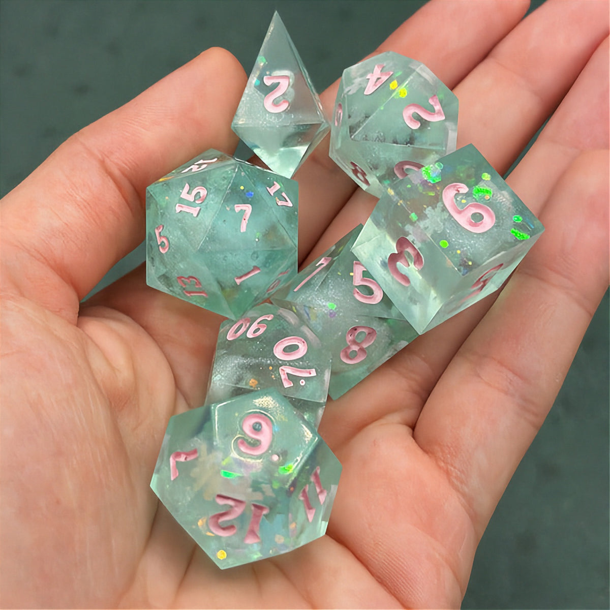 Set of green polyhedral dice with pink numbers on a dark background with star patterns