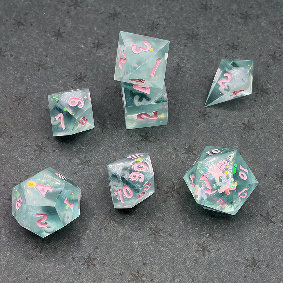Set of green polyhedral dice with pink numbers on a dark background with star patterns