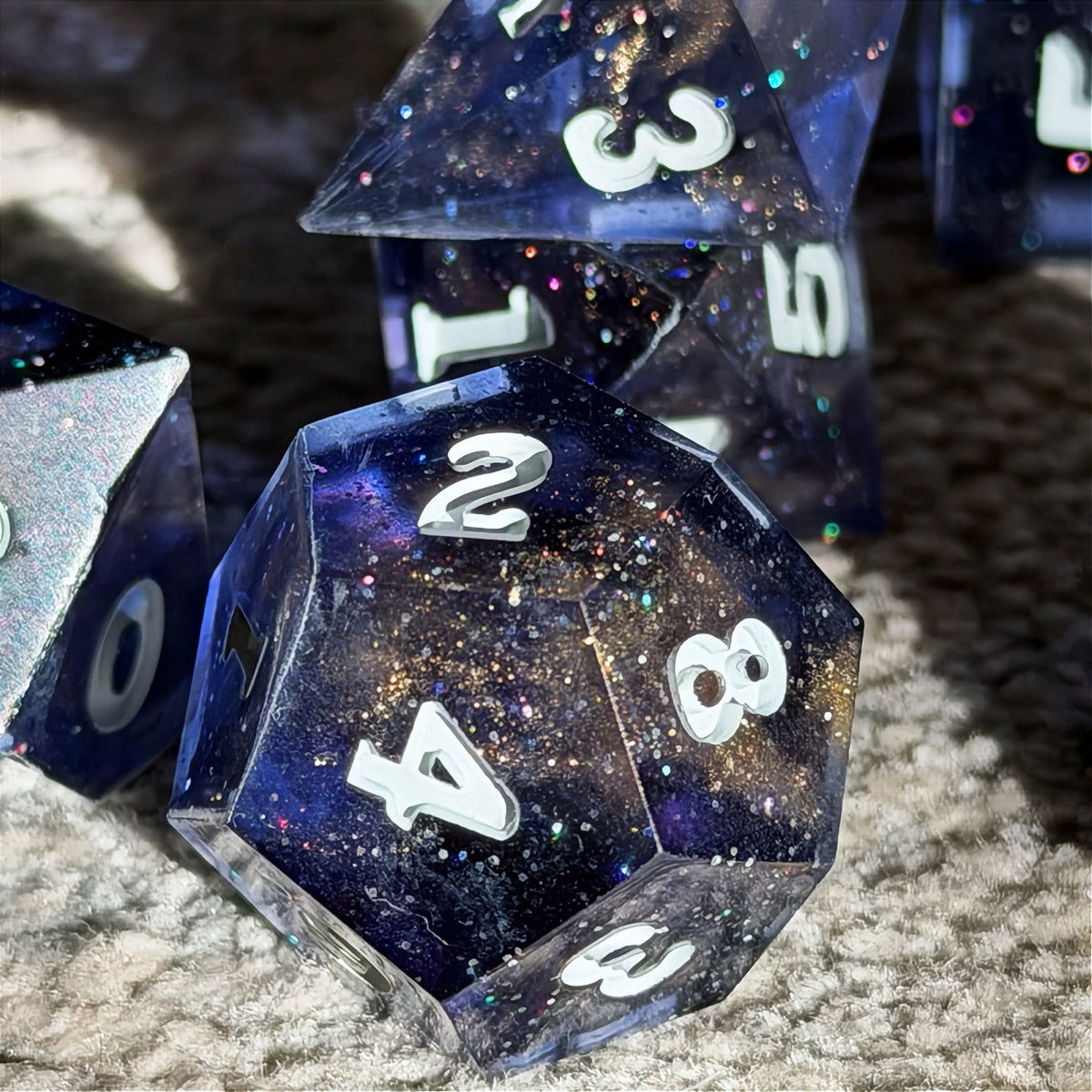 Set of polyhedral dice in a tin with star and moon pattern