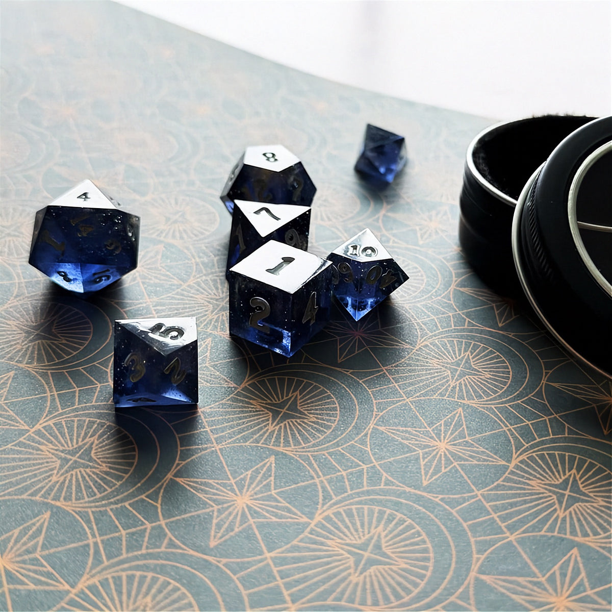 Set of polyhedral dice in a tin with star and moon pattern