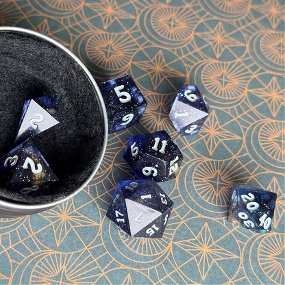 Set of polyhedral dice in a tin with star and moon pattern