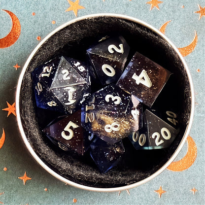Set of polyhedral dice in a tin with star and moon pattern