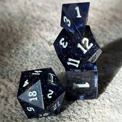 Set of polyhedral dice in a tin with star and moon pattern