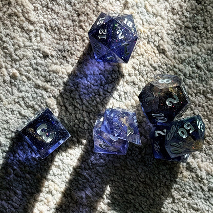 Set of polyhedral dice in a tin with star and moon pattern