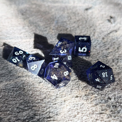 Set of polyhedral dice in a tin with star and moon pattern