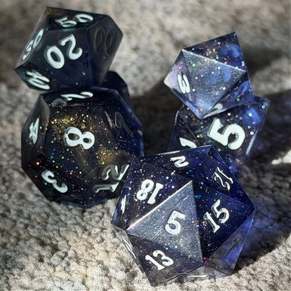 Set of polyhedral dice in a tin with star and moon pattern