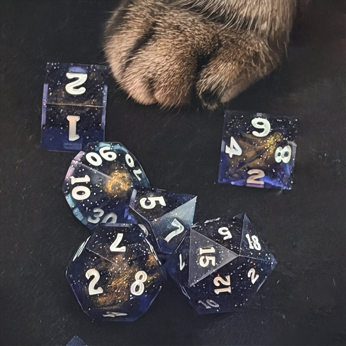 Set of polyhedral dice in a tin with star and moon pattern