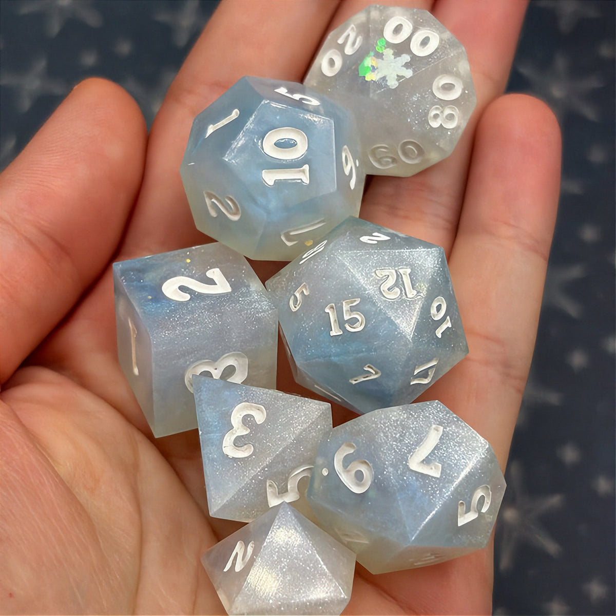 Set of light blue polyhedral dice on a dark background with star patterns