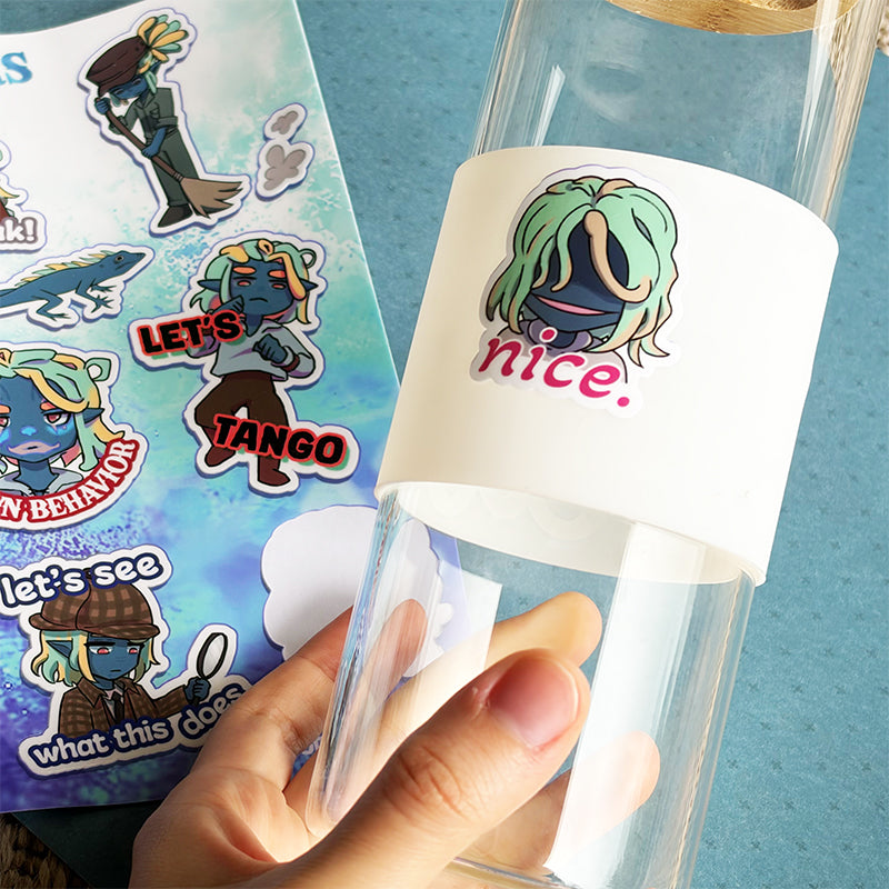 Clear cup with cartoon character sticker and colorful sticker sheet on a blue background