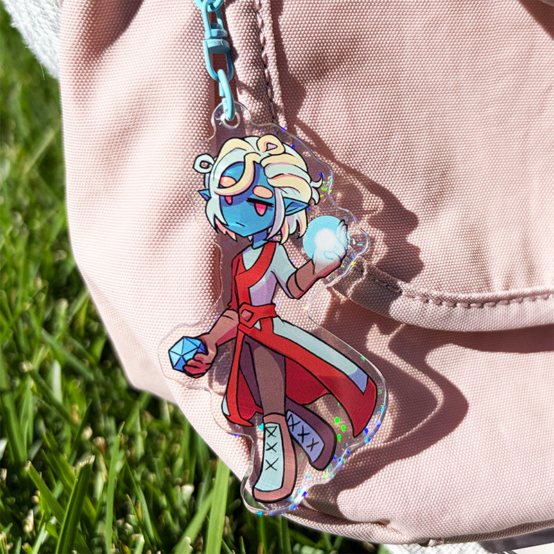 Colorful character keychain attached to a beige jacket with grass in the background